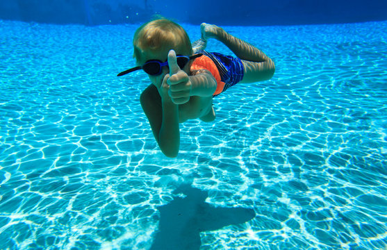 happy little boy swimming underwater wtih thumb up