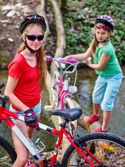 Naklejka premium Bikes cycling girl. Girl rides bicycle. Girl cycling fording throught water on log. Cycling trip is good for health. Cyclist watch your step.