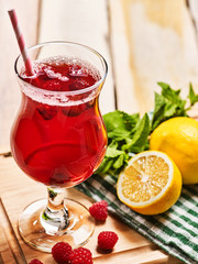 On wooden boards is ice cold beverage glass with red raspberry lemon cocktail . Alcohol country cocktail beverage number ninety six with raspberry clay bowl. Top view cocktail .