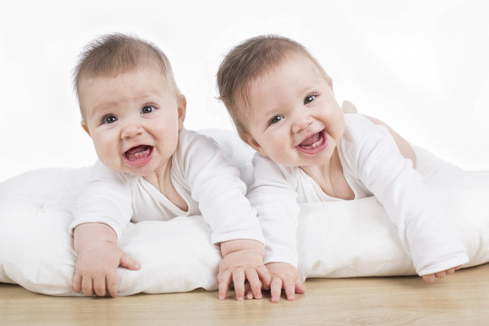 smiling happy twin baby girls on tummy