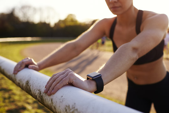 Young Woman Wearing Activity Tracker Stretches Before Run