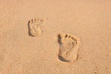 stamp of feet on sand on the beach with sunshine in the morning