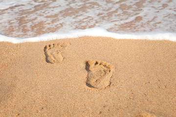 stamp of feet on sand on the beach with sunshine in the morning