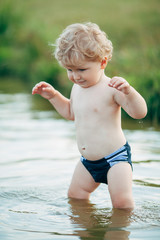 Fototapeta na wymiar little funny boy playing in water