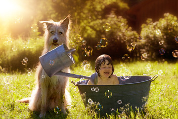 Sommerhitze, Hund duscht Kleinkind mit Gießkanne