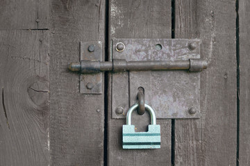 Green lock on a grey wooden door