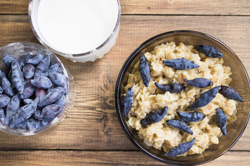 oatmeal with berries honeysuckle and drinking yoghurt on the background of old wooden planks