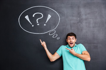Wondered man pointing on thinking bubble over blackboard background