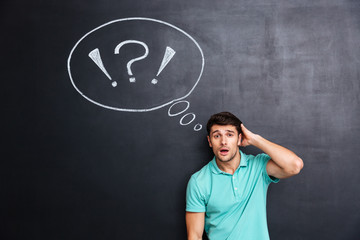 Puzzled confuzed young man over chalkboard background