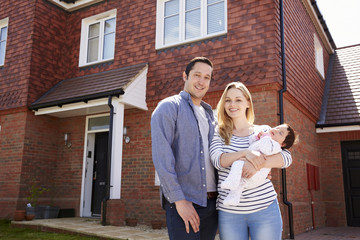 Portrait Of Young Family Standing Outside New Home