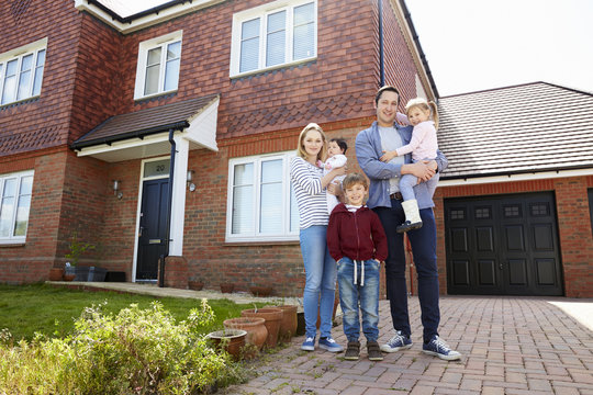 Portrait Of Young Family Standing Outside New Home