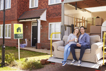 Couple With Sofa On Tail Lift Of Removal Truck Moving Home