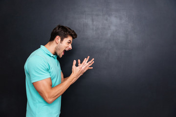 Side view of a angry man screaming over black background