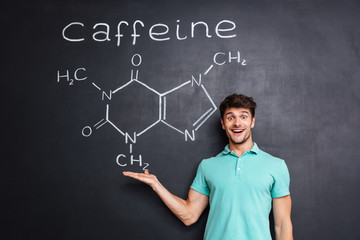 Cheerful young scientist showing chemical structure of caffeine molecule