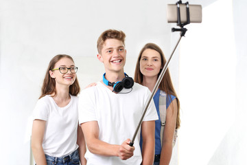 Selfie. Grupa przyjaciół robi zdjęcie selfi telefonem umieszczonym na monopodzie - obrazy, fototapety, plakaty