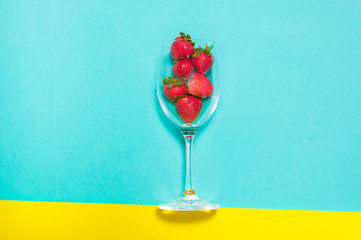 Fresh strawberry in a cup on blue and yellow background. Creative strawberry flat lay.