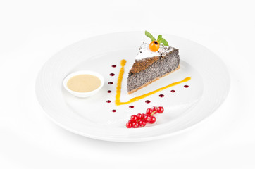 Poppy seed cake with winter cherry, red currant and vanilla sauce on a white background