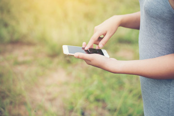 Young woman hands typing smartphone in the park.