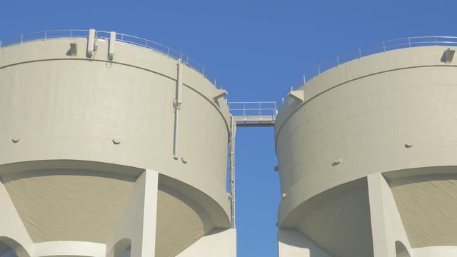 Water tanks made of concrete against blue sky 4K 2160p UHD slow panning video - Water tower in front of blue sky 4K 3840X2160 panning UHD footage 