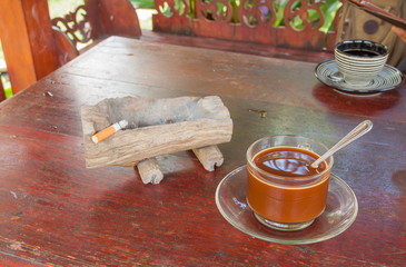 Coffee cup on a wooden table with Cigarette Ashtray.