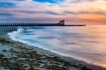 Fototapeta premium Coast with piles during sunset, long exposure blurring water.Baltic, Poland.
