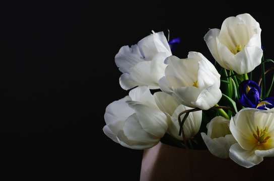 bouquet of a white tulips and blue irises in the paper bag on a