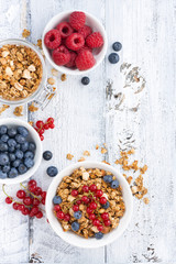 granola and fresh berries on white wooden background, vertical