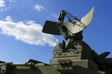 Air defense radar of military mobile mighty missile launcher system of green color, modern army industry, white cloud and blue sky on background  - obrazy, fototapety, plakaty