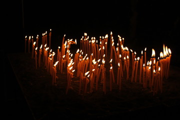 Thin candles lightening in the darkness, spiritual glowing in monastery, © Monik-a