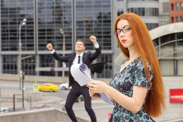 Red-haired businesswoman and businessman on background