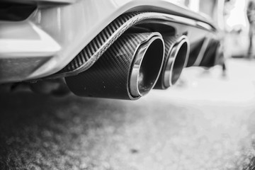 Double exhaust pipes of a modern sports car, black and white - obrazy, fototapety, plakaty