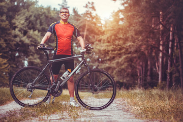 Obraz premium man cyclist rides in the forest on a mountain bike.