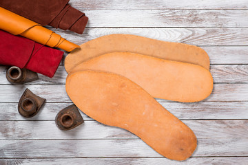 Set of leather in rolls, craft tools on white wooden background. Workplace for shoemaker. Working...