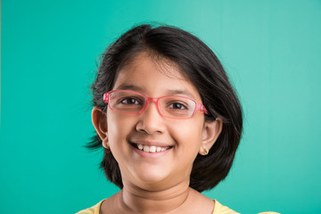Happy little indian girl smiling while wearing glasses, green background, indian small girl wearing...