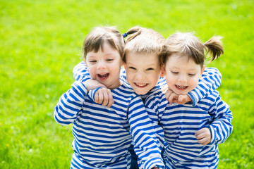Fototapeta na wymiar Three adorable little kids in striped T-shirts outdoors at warm summer day