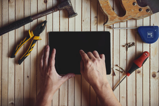 Close-up of male hands touching screen of digital computer pc on worktable with instruments. Concept of handicraft, project and technology.
