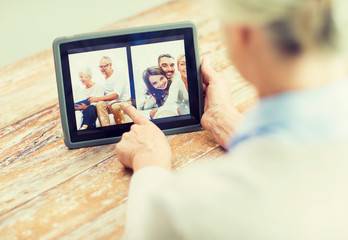 Fototapeta na wymiar senior woman with family photo on tablet pc screen
