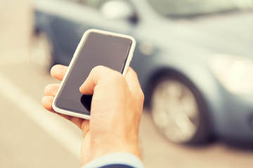 close up of man hand with smartphone and car
