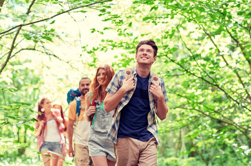 group of smiling friends with backpacks hiking