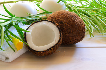 Coconut, towel towel with tropical flower and candles on light wood background for  spa concept.