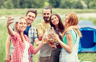 happy friends taking selfie by smartphone at camp