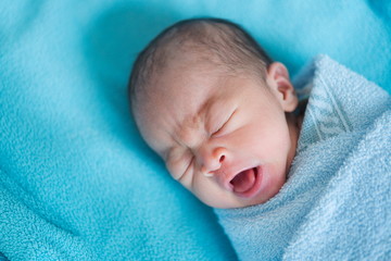 Newborn baby Asia  while sleeping covered with blue cloth