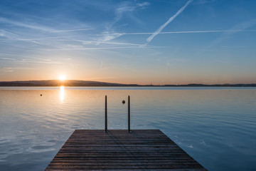 Fototapeta na wymiar Jump. Relaxing quiet evening on the lake. Setting sun is reflected in water. Switzerland.