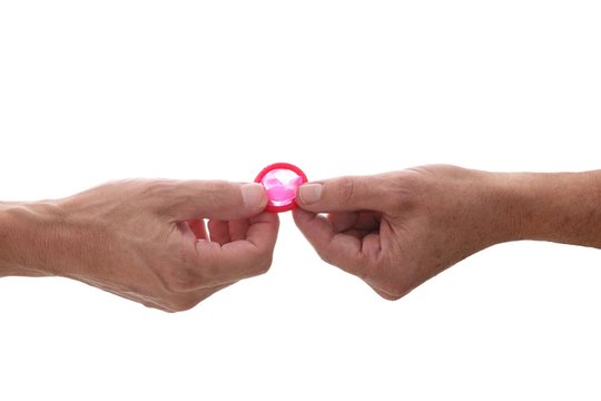 male gay couple hands giving condom