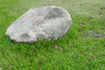 Big stone, on green grass in the garden  