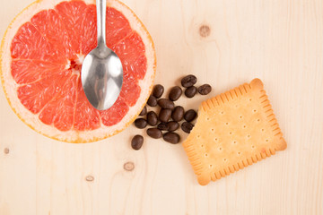 Cakes coffee beans cookies, grapefruit, under wooden background
