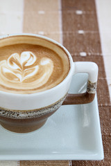 A cup of hot cappuccino on table.