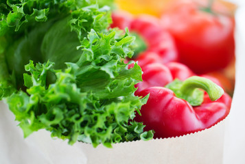 close up of paper bag with vegetables and greens