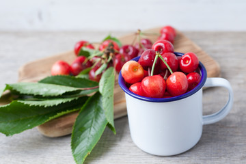Cherries in enamel mug on the table close up, selective focus