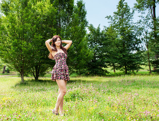 Naklejka na ściany i meble young beautiful brunette standing on the grass